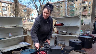 Una mujer cocina en el patio de un complejo de edificios de apartamentos dañado por los ataques de Rusia en las afueras de Mariúpol, Ucrania, el martes 29 de marzo de 2022.