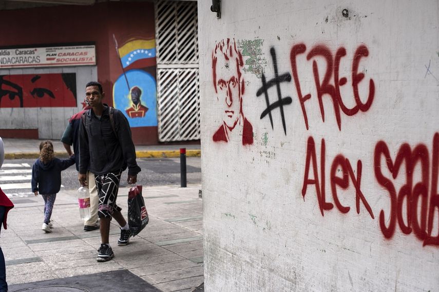 La gente camina cerca de un grafiti exigiendo la libertad del empresario colombiano Alex Saab, en el oeste de Caracas, el 23 de febrero de 2021.&nbsp;&nbsp;