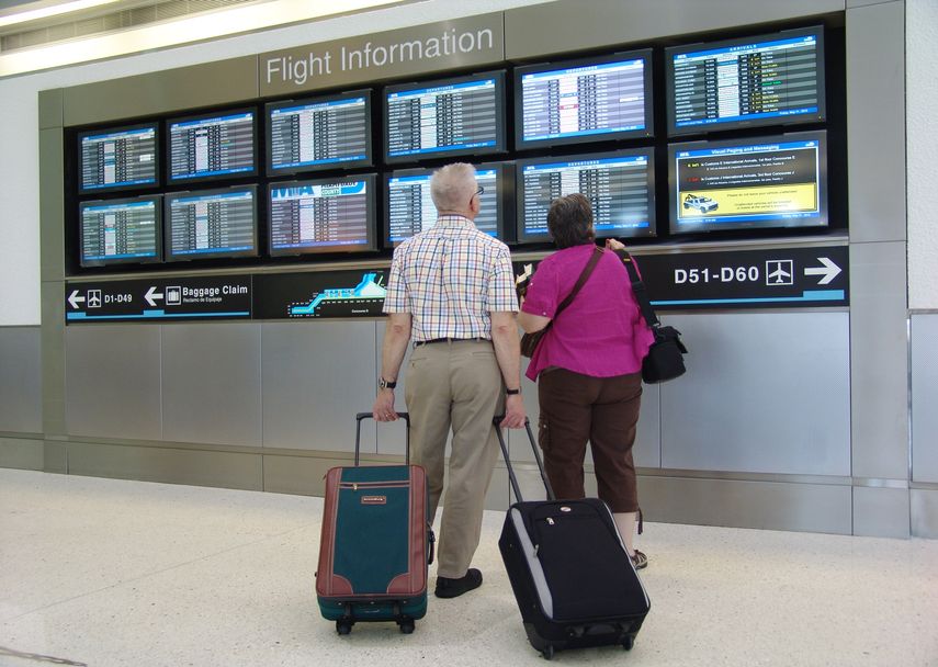 Dos pasajeros verifican hora de salida de su vuelo en el Aeropuerto Internacional de Miami.
