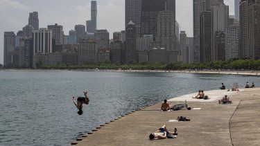 Un hombre se arroja al lago Michigan mientras otras personas se asolean en medio de un intenso calor el miércoles 15 de junio de 2022, en Chicago.&nbsp;