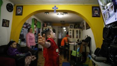 Santi, de seis años, realiza ejercicios frente al televisor durante un segmento de educación física en una clase para nivel kínder, mientras su madre, Denisse, y su hermana de cinco años, Liz, observan la transmisión desde casa, en Ciudad de México, el lunes 24 de agosto de 2020.
