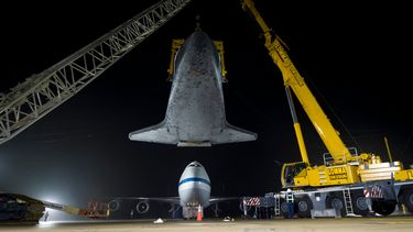 Esta foto de la NASA muestra el transbordador espacial Discovery, suspendido de una eslinga sostenida por dos grúas, mientras el 747 Shuttle Carrier Aircraft (SCA) de la NASA es empujado hacia atrás desde abajo en el Aeropuerto Internacional Washington-Dulles, el 19 de abril de 2012, en Sterling, Virginia.