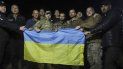 En esta imagen, distribuida por el servicio de prensa de las fuerzas de seguridad de Ucrania, soldados ucranianos liberados en un intercambio de prisioneros con Rusia, posan con una bandera de Ucrania cerca de Cherníhiv, Ucrania, el 21 de septiembre de 2022. 