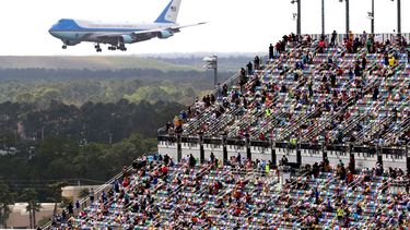 Aficionados de las carreras observan desde las gradas cuando el avión Air Force One da una vuelta sobre el circuito Daytona mientras el presidente Donald Trump llega para asistir a la carrera de autos NASCAR Daytona 500 en la Daytona International Speedway el domingo 16 de febrero de 2020 en Dayton Beach, Florida. 