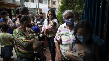 Varias mujeres y niños, con mascarillas para protegerse del coronavirus, aguardan su turno el viernes 20 de noviembre de 2020 durante una campaña de vacunación contra otras enfermedades organizada por el Ministerio de Salud, en el vecindario El Valle, en Caracas, Venezuela.
