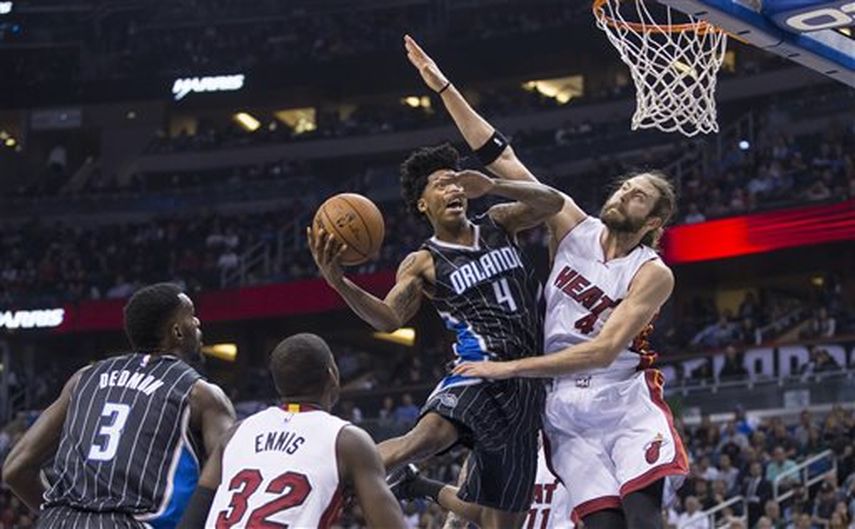 Elfrid Payton (4) se lanza hacia la canasta ante la defensa del jugador del Heat Josh McRoberts. (AP)