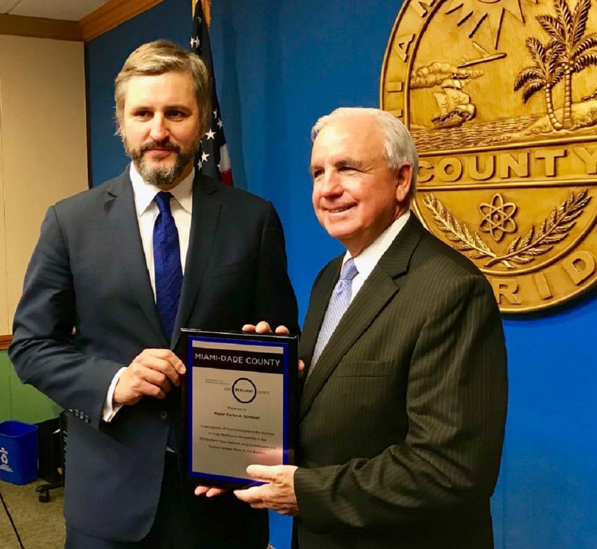 El alcalde Carlos Giménez (der.), recibe la placa que acredita a Miami-Dade como miembro de la iniciativa de 100 ciudades resilientes de manos de Michael Berkowitz, presidente de este proyecto.