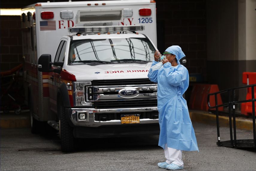 Una enfermera de urgencias se pone un protector facial despu&eacute;s de tomar un descanso junto al estacionamiento de ambulancias y otros veh&iacute;culos de emergencias m&eacute;dicas fuera del Brooklyn Hospital Center en Nueva York.&nbsp;