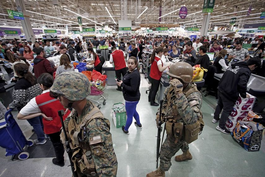 La policía militar hace guardia en un supermercado mientras los clientes pagan por sus compras, en Santiago, Chile, el lunes 21 de octubre de 2019.