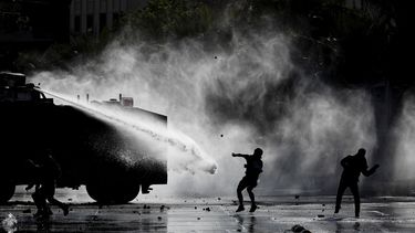 Manifestantes se enfrentan con la policía, que les rocía agua, durante una protesta contra el gobierno en Santiago de Chile el martes 5 de noviembre de 2019