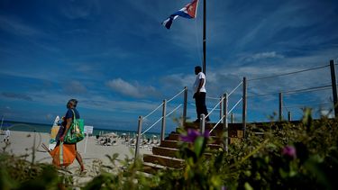 Un turista camina cerca de una bandera nacional cubana en el Hotel Melia International Varadero en la provincia de Matanzas, el 23 de octubre de 2020. Varadero, el balneario más importante de Cuba, reabre al turismo internacional, en medio de la pandemia del coronavirus.