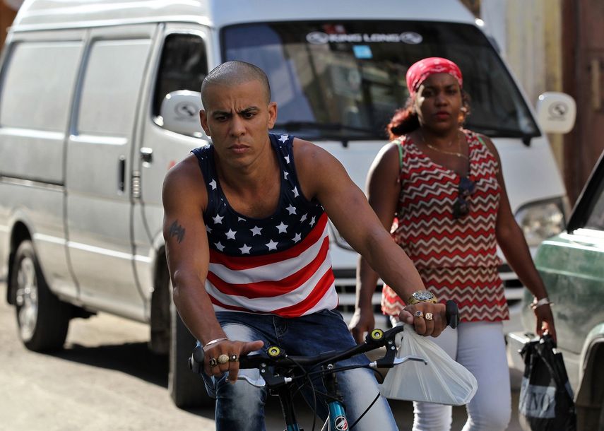 Un joven cubano vestido con una camiseta alusiva a la bandera de EEUU circula en bicicleta por las calles de La Habana el martes 13 de junio.&nbsp;