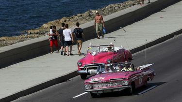 Un grupo de turistas viaja en un viejo descapotable del pasado siglo por el malecón de La Habana. Toparse con visitantes de Estados Unidos por La Habana es cada vez más habitual, atraídos por los coches antiguos que todavía circulan por su calles y sus ed