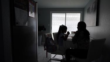 Una mujer ayuda a sus dos hijos con sus tareas en su casa, el martes 19 de abril de 2022 en Tampa, Florida.&nbsp;