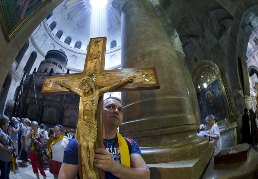 Un cristiano porta una cruz de madera por la nave central de la Iglesia del Santo Sepulcro, en Jerusalén.&nbsp;