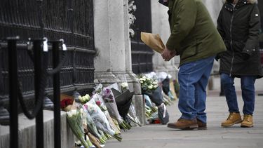 Un hombre deja un ramo de flores en la puerta del Palacio de Buckingham, en Londres, el 10 de abril de 2021, un día después de la muerte del príncipe Felipe, el marido de la reina Isabel II.&nbsp;