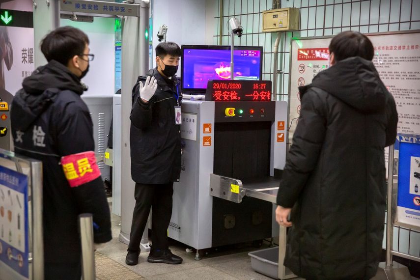 Personal de seguridad da instrucciones a un individuo al cruzar una cámara infrarroja en una estación del metro de Beijing, el miércoles 29 de enero de 2020