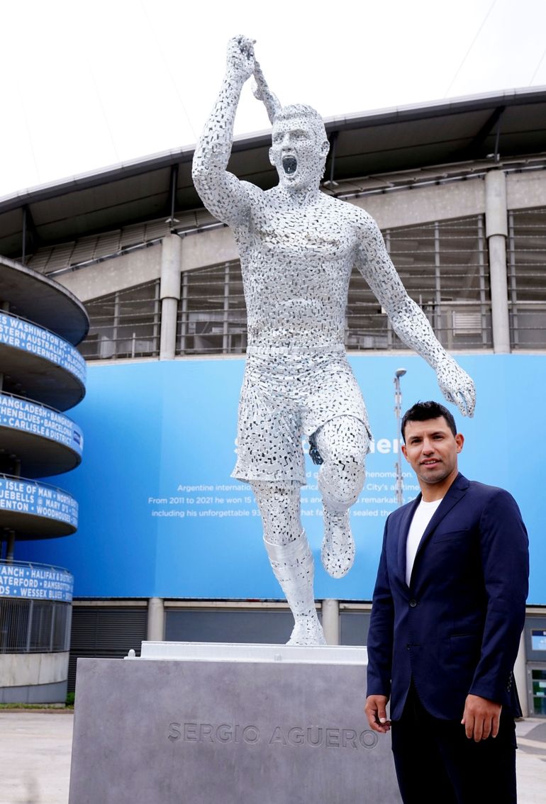El argentino Sergio Agüero posa ante su estatua que fue develada por el Manchester City afuera del Estadio Etihad, en Manchester, Inglaterra, el viernes 13 de mayo de 2022. 