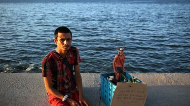 Un hombre pide limosna con una imagen del milagroso San Lázaro hoy, martes 18 de julio de 2017, en el malecón de La Habana (Cuba).