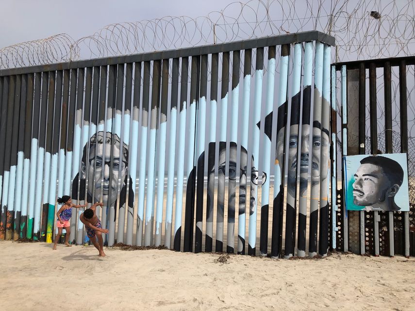Dos niños juegan frente a un nuevo mural en el lado mexicano del muro fronterizo en Tijuana, México.