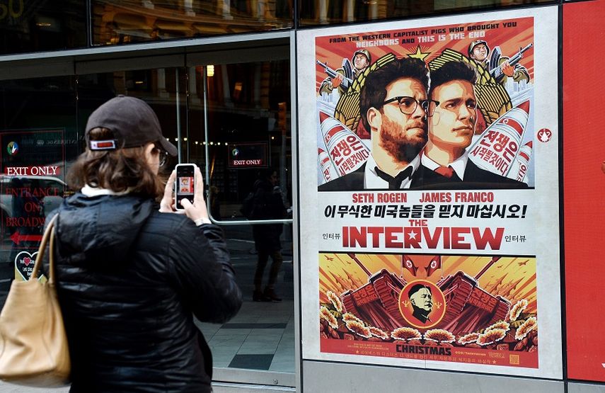 Una mujer toma una foto del afiche promocional de la cina The Interview en la sala de cine Regal de Nueva York, 2014. (EFE). 