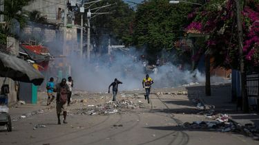 Manifestantes corren después de que la policía arrojara gases lacrimógenos durante una protesta para exigir la renuncia del primer ministro Ariel Henry, el lunes 3 de octubre de 2022
