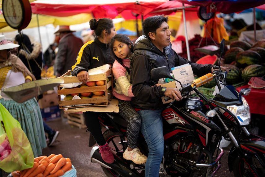 Una familia transporta frutas y verduras en su motocicleta en un mercado popular de comida en Puno, Perú, el 29 de enero de 2023.