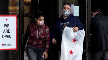 Dos personas salen de una tienda Macys con sus compras.
