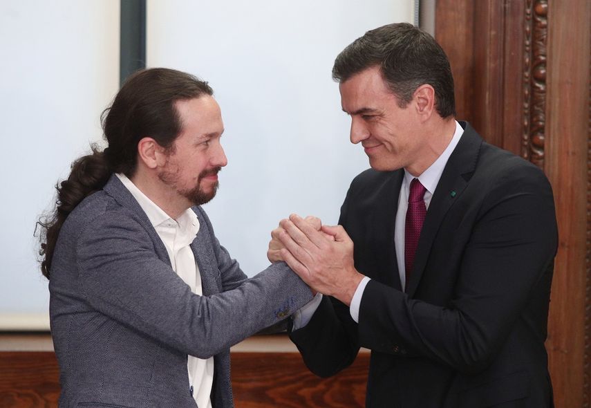 El presidente del Gobierno en funciones, Pedro Sánchez (dech.) y el secretario general de Podemos, Pablo Iglesias (izq), se dan la mano durante el acto de presentación del programa de Gobierno del PSOE y Unidas Podemos, en el Congreso de los Diputados, Madrid (España), a 30 de diciembre de 2019. 