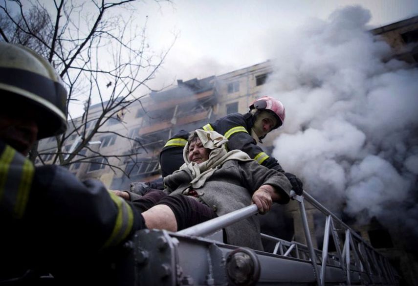 En esta imagen cortesía del Servicio Estatal de Emergencia de Ucrania, bomberos evacúan a una anciana de un edificio de apartamentos que fue bombardeado, el lunes 14 de marzo de 2022, en Kiev, Ucrania.&nbsp;