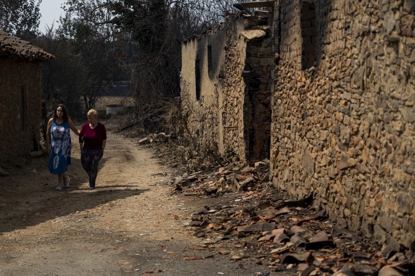 Vecinas de Castrocalbón junto a una vivienda que ha sido destruida por los incendios, a 20 de agosto de 2025, en Castrocalbón, León, Castilla y León (España).