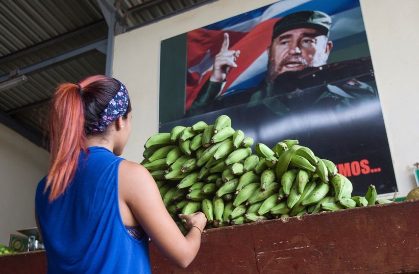 Una mujer es vista en un agromercado en el que se observa una foto del fallecido dictador Fidel Castro en La Habana, Cuba.&nbsp;
