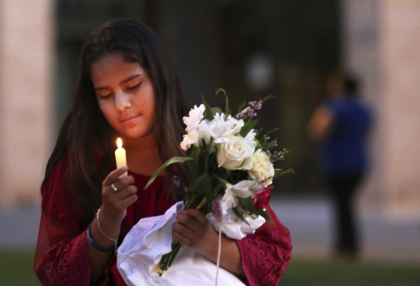 En esta imagen del 1 de septiembre de 2019, Jaxciri Solano enciende una vela y sostiene un ramo de flores al inicio de una vigilia en el campus de UTPB en Odessa, Texas, en memoria de las víctimas de un tiroteo el sábado.&nbsp;&nbsp;