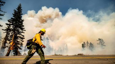 Un bombero camina por la autopista 89 frente al incendio forestal Dixie en el Bosque Navional Lassen, California
