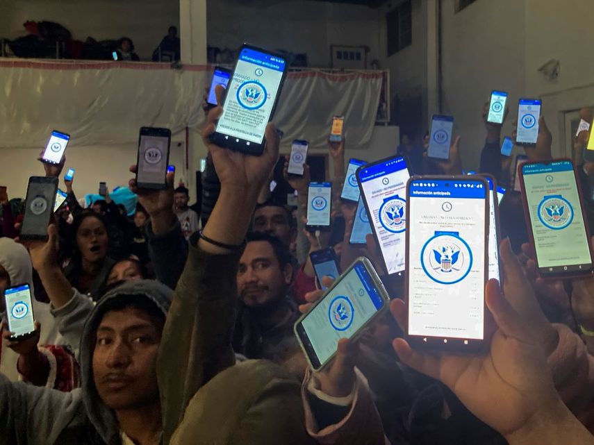 Decenas de migrantes muestran sus teléfonos el domingo 22 de enero de 2023 mostrando en ellos la app CBPOne, en un albergue en México.