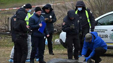 Expertos policiales examinan un cuerpo exhumado de una fosa común en los terrenos de la iglesia de Todos los Santos de San Andrés y Pyervozvannoho en la ciudad ucraniana de Bucha, al noroeste de Kiev, el 13 de abril de 2022.&nbsp;