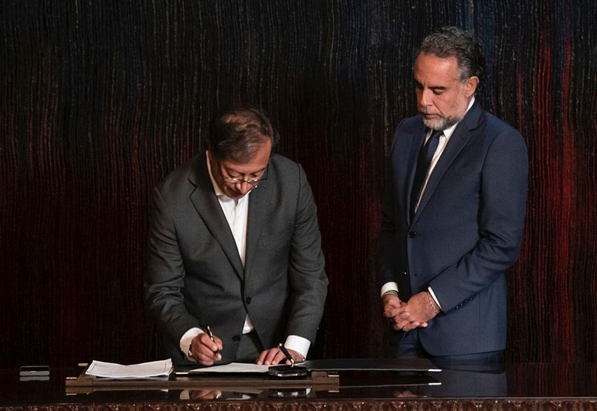 En esta foto proporcionada por la presidencia de Colombia el 24 de agosto de 2022, el presidente Gustavo Petro (izq.) firma un decreto que designa a Mario Benedetti como nuevo embajador en Venezuela, en el palacio presidencial de Nariño en Bogotá.
