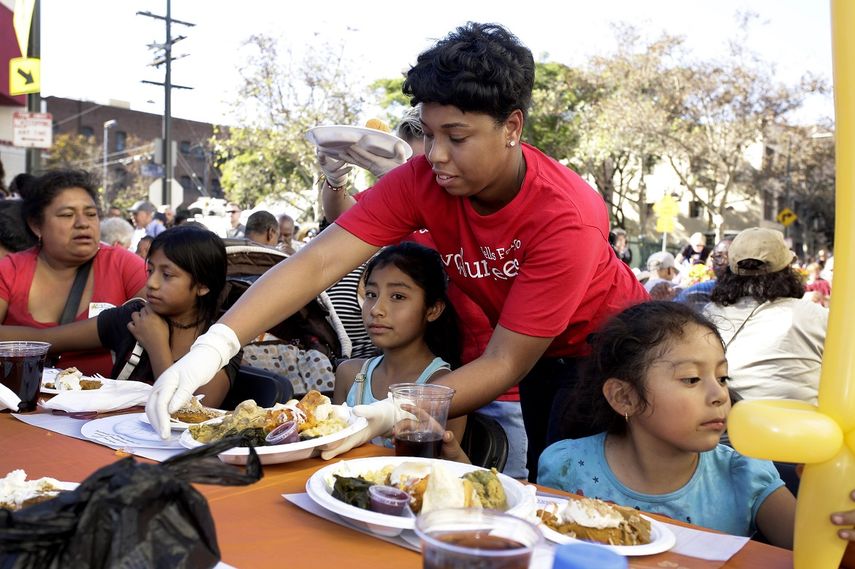 Fotografía de archivo fechada en noviembre de 2017 de una voluntaria entregando comida a un grupo de personas sin hogar en Los Ángeles, California.