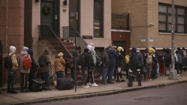 Migrantes hacen fila a la intemperie en el exterior de un centro de ayuda habilitado en la escuela primaria Santa Brígida, en Nueva York.&nbsp;