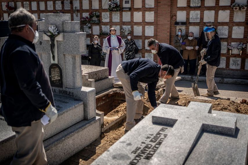 &nbsp; Un sacerdote y varios dolientes rezan mientras una v&iacute;ctima del COVID-19 es enterrada en el cementerio de la Almudena, en Madrid, el s&aacute;bado 28 de marzo de 2020.&nbsp; &nbsp;