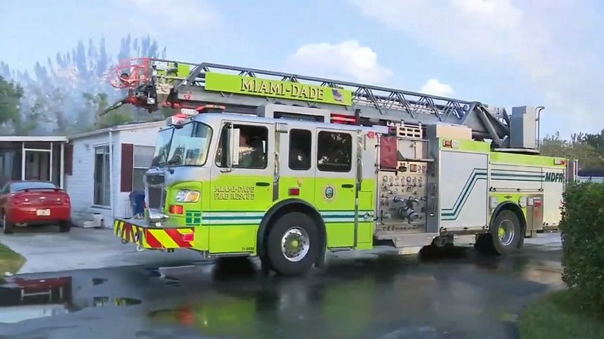 Un camión del Cuerpo de Bomberos de Miami-Dade pasa frente a una vivienda en Florida City, amenazada por un incendio.
