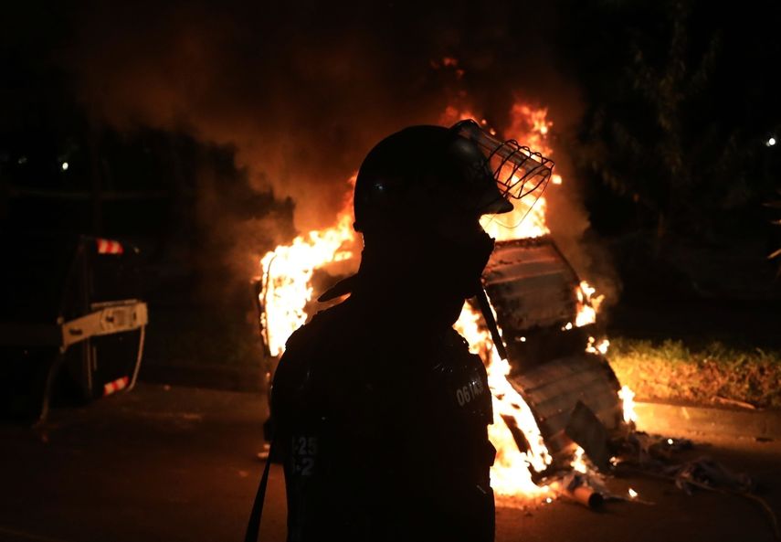 Un agente antimotines est&aacute; parado detr&aacute;s de una barricada en llamas durante las protestas por la muerte de un hombre a manos de la polic&iacute;a que lo detuvo por violar el distanciamiento social, en Bogot&aacute;,, 10 de septiembre de 2020.&nbsp;