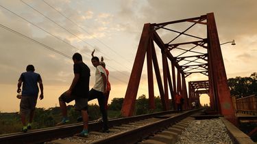 Migrantes hondureños conversan en una vía férrea de la población de Huixtla (México) donde permanecen en su travesía hacia Estados Unidos.&nbsp;