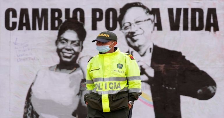 Un oficial de policía hace guardia cerca de un cartel de campaña del candidato presidencial Gustavo Petro y su compañera de fórmula Francia Márquez.
