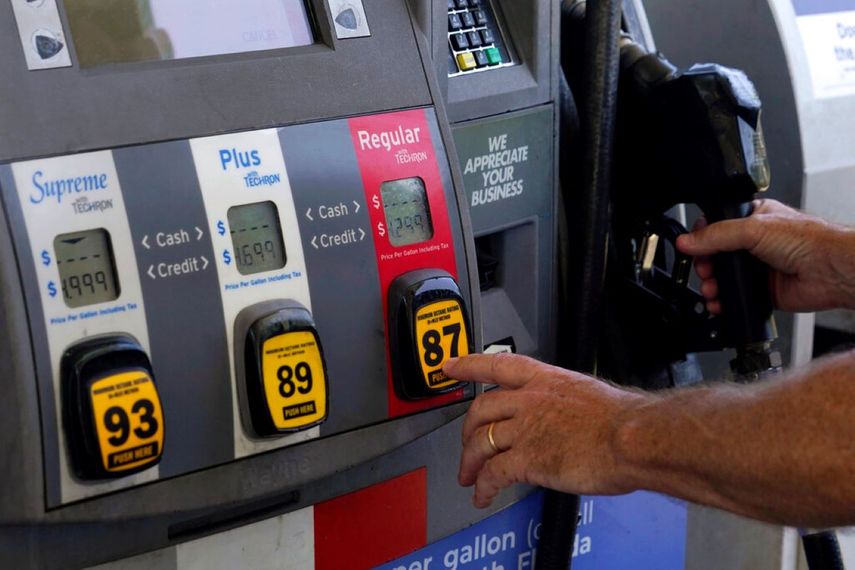 Una persona aprieta el botón que marca el octanaje para echar combustible a su auto.