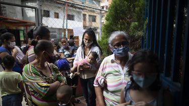 Varias mujeres y niños, con mascarillas para protegerse del coronavirus, aguardan su turno el viernes 20 de noviembre de 2020 durante una campaña de vacunación contra otras enfermedades organizada por el Ministerio de Salud, en el vecindario El Valle, en Caracas, Venezuela.
