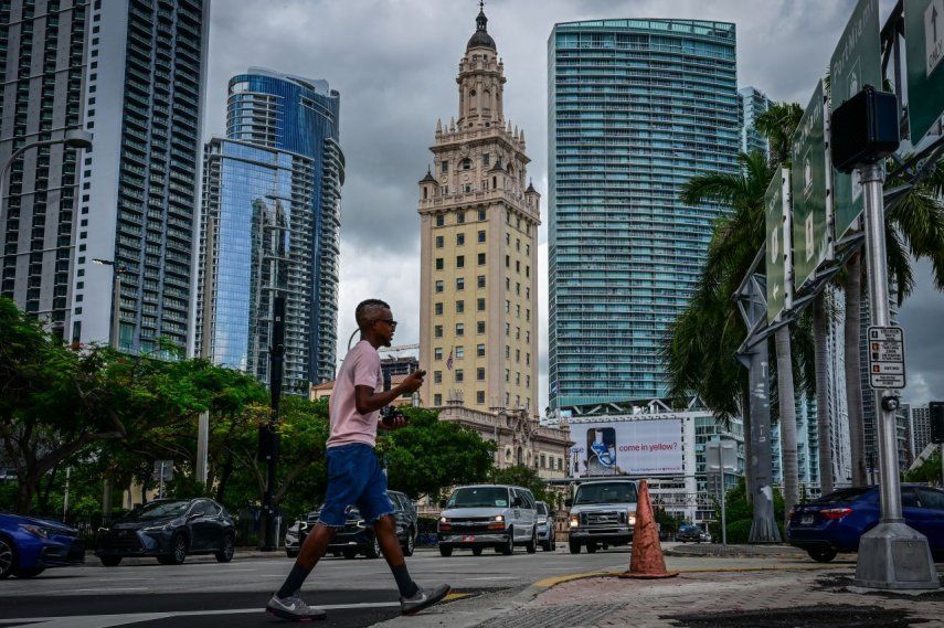 La foto muestra un transeúnte cruzando una calle en la ciudad de Miami, Florida.