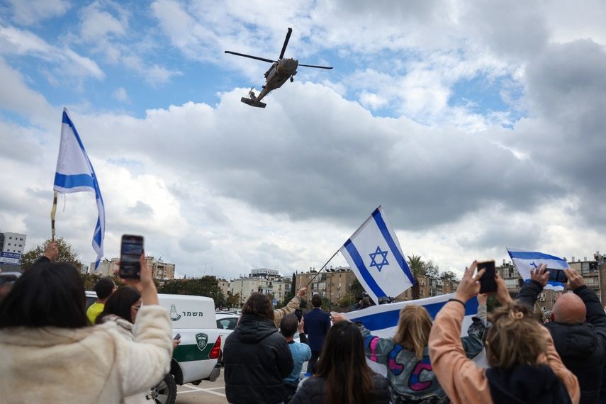 La gente vitorea y ondea banderas israelíes mientras un helicóptero militar que transporta al rehén israelí recién liberado Tal Shoham llega al Hospital Beilinson en el Centro Médico Rabin en Petah Tikva, en el centro de Israel, el 22 de febrero de 2025.