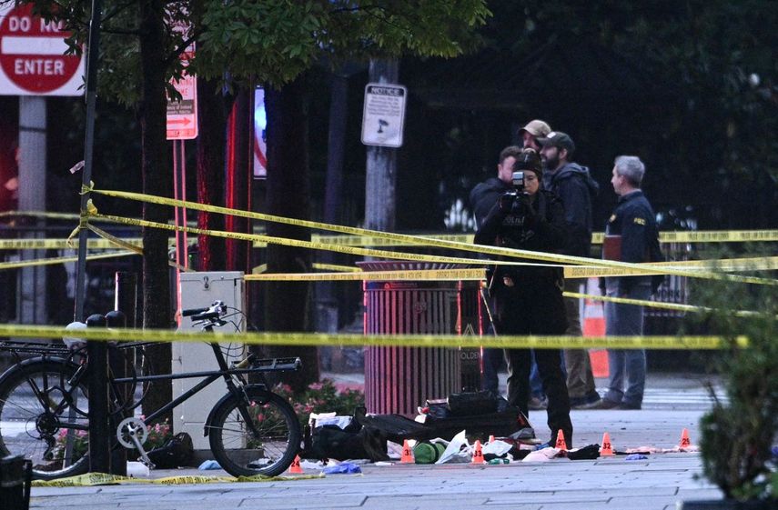 Un investigador forense toma fotos detrás de una cinta policial que protege la escena del crimen, con marcadores de evidencia visibles en una acera en la 17ª y la avenida Pennsylvania cerca de la Casa Blanca en Washington, DC, el 23 de mayo de 2026.
