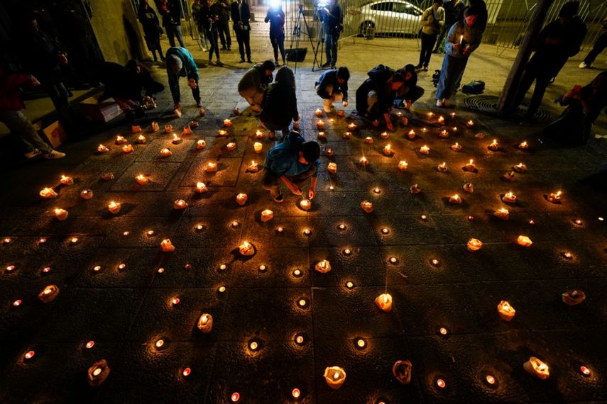 Las personas encienden velas durante una vigilia frente a la sede de los Carabineros en honor a tres policías asesinados, en el sur de Chile.